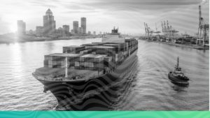 A large container cargo ship navigating green ocean waters near a port representing UK CBAM and global carbon trade compliance.